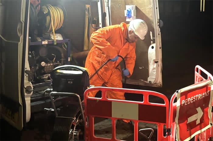 A drainage engineer unblocking a blocked drain a night